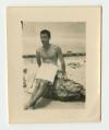 Arthur Howe, Jr. on a beach in North Africa, sitting on a rock. Contact Print recto