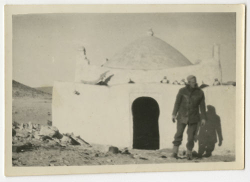 Charles "Chuck" O'Neill in front of a small building in the desert. Recto