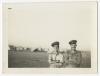 Two unidentified individuals, with tent camp in the background