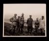 Group of unidentified individuals outside, with vehicles in the background